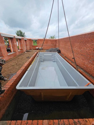 Установка композитного бассейна с помощью крана в строительном котловане